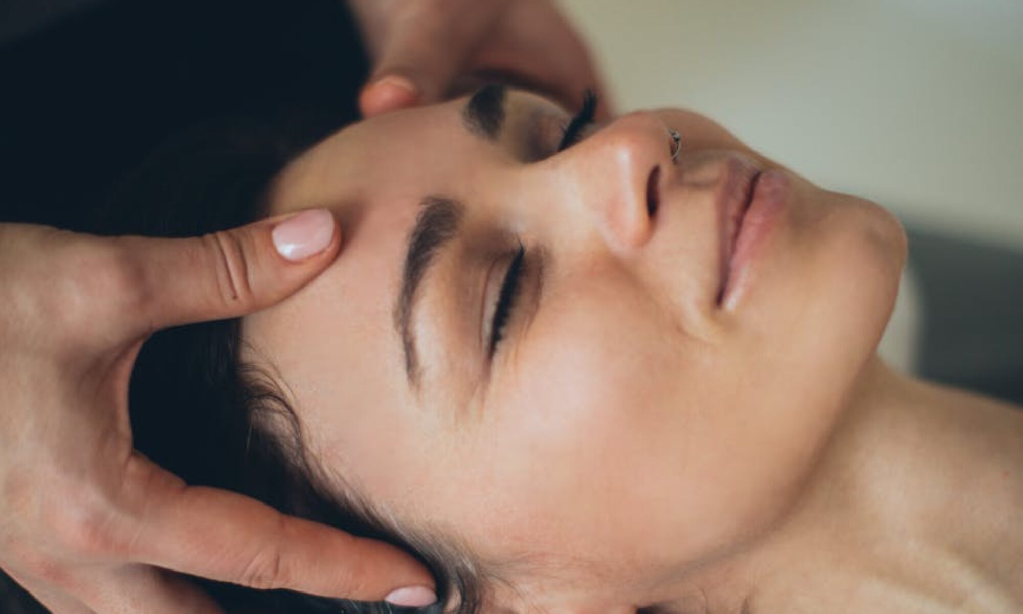 a woman lying down while having her head massage by a person