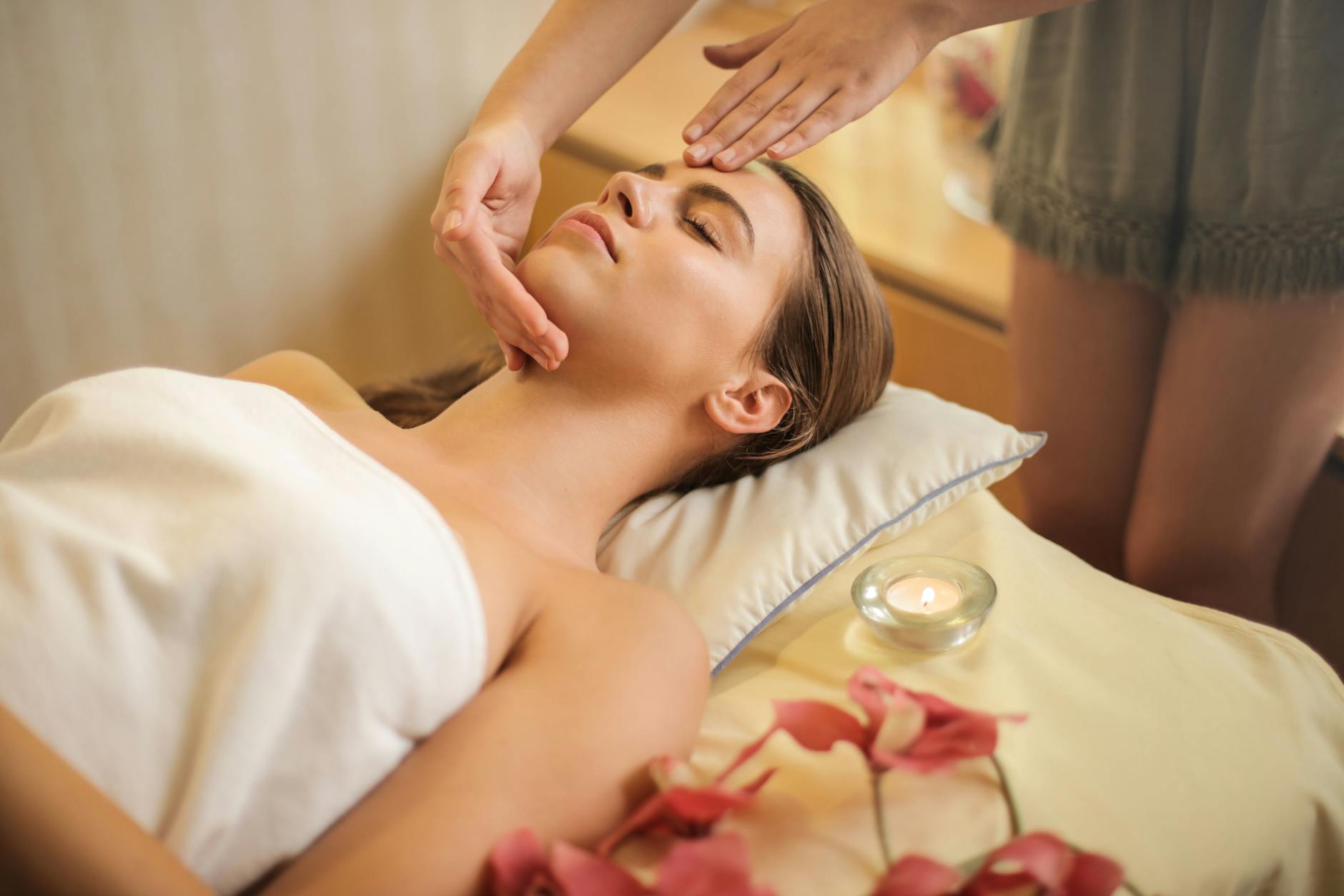 woman in wrapped in white towel lying on bed getting massage